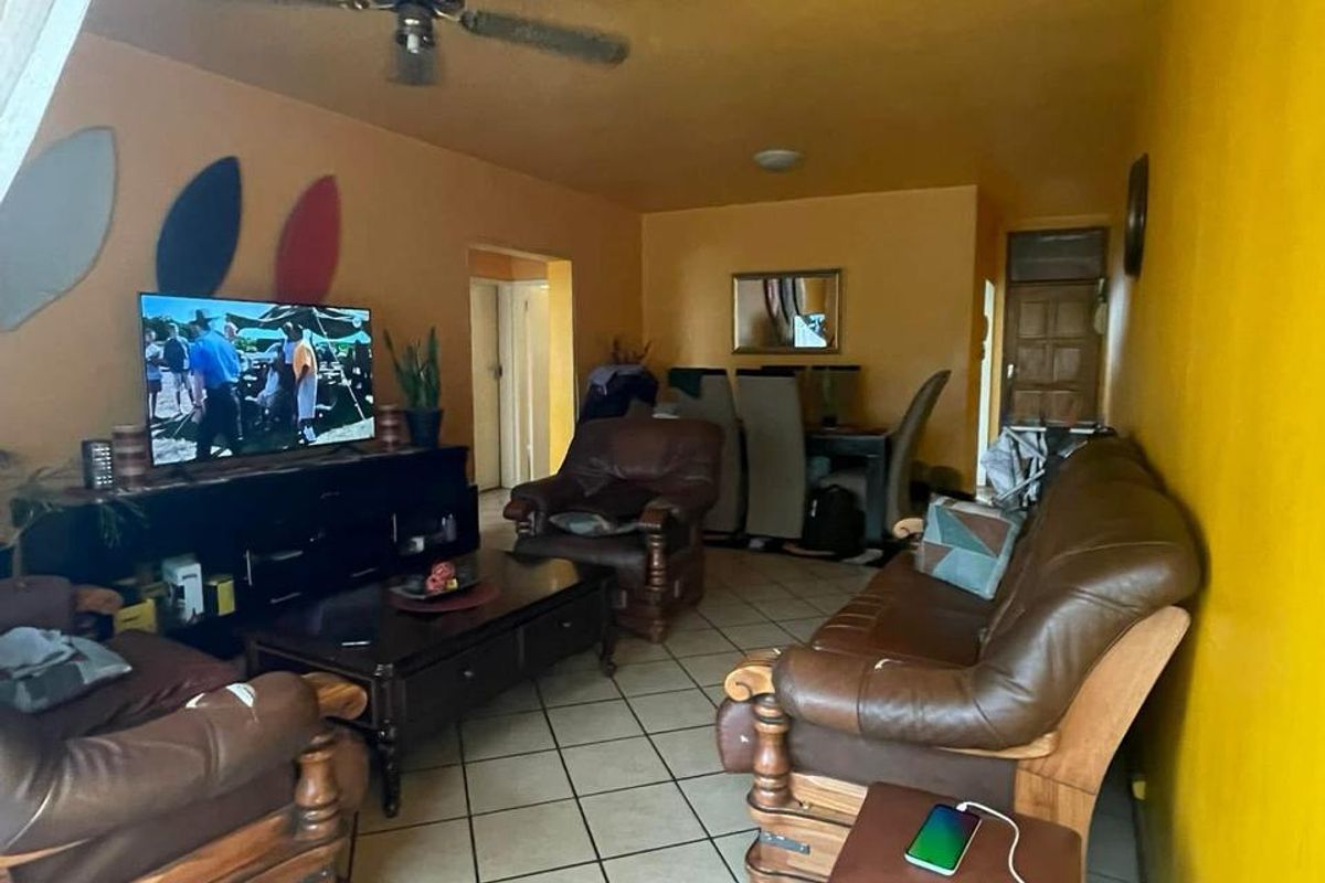A living room featuring tiled flooring and a ceiling fan, providing a functional space with potential for modernization.