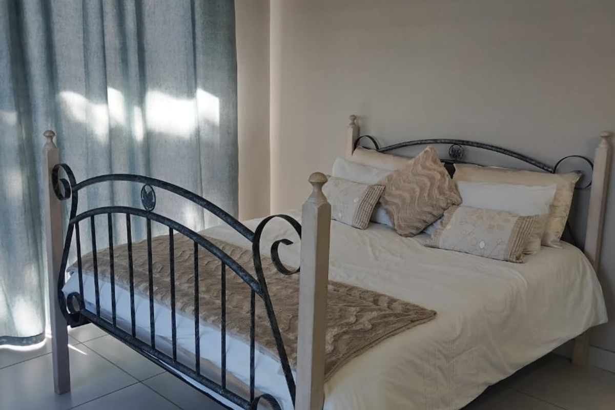 A bedroom featuring neutral wall tones and large format floor tiles, with a sliding door providing access to natural light.