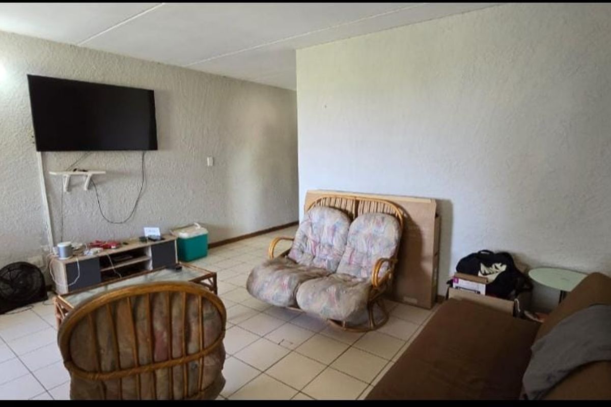 A living room area featuring textured walls and tiled flooring, providing a functional space for relaxation.