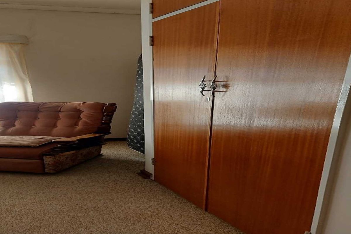 A bedroom featuring built-in wooden cupboards and carpeted flooring.