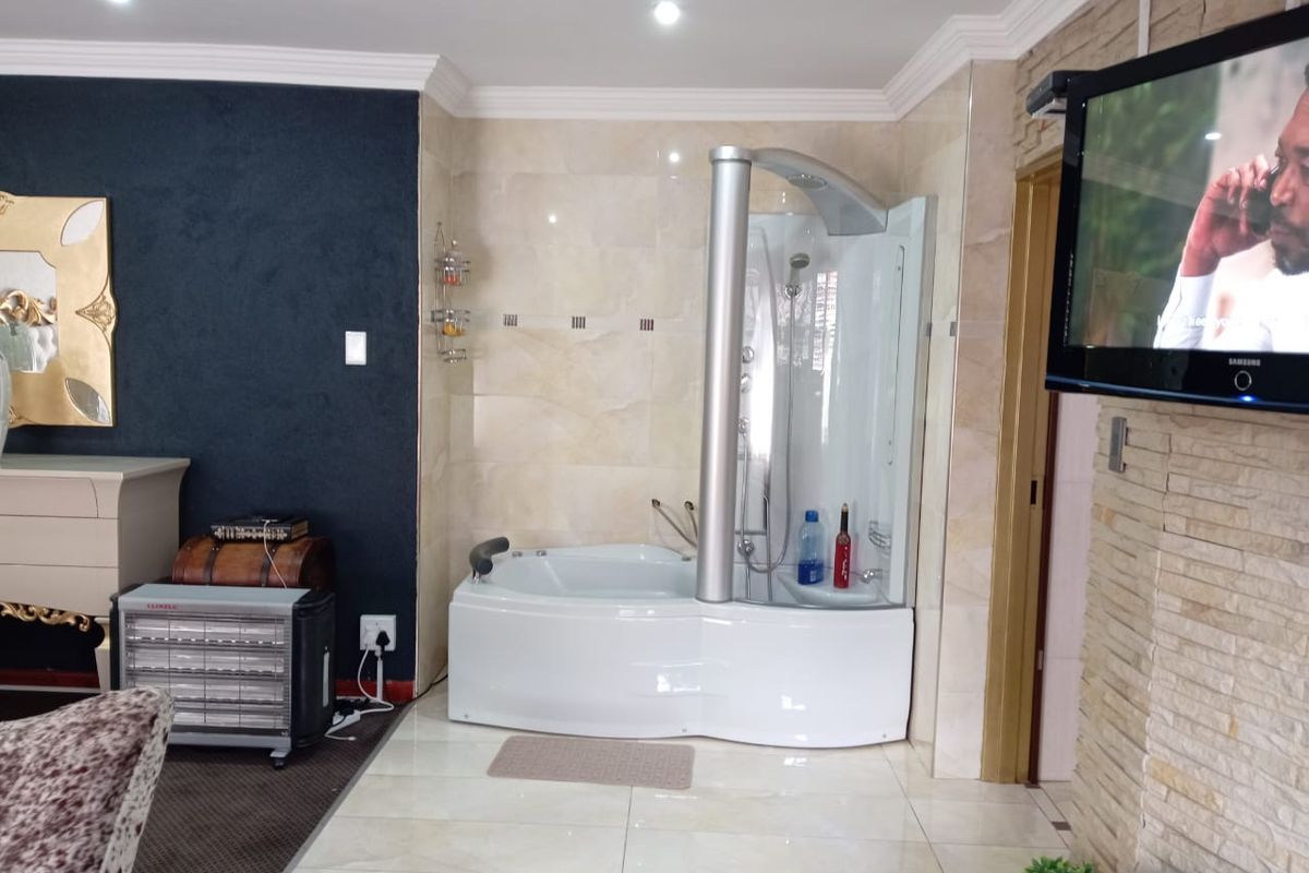 A bathroom area featuring a modern integrated shower and bathtub unit, tiled flooring, and decorative stone wall cladding.
