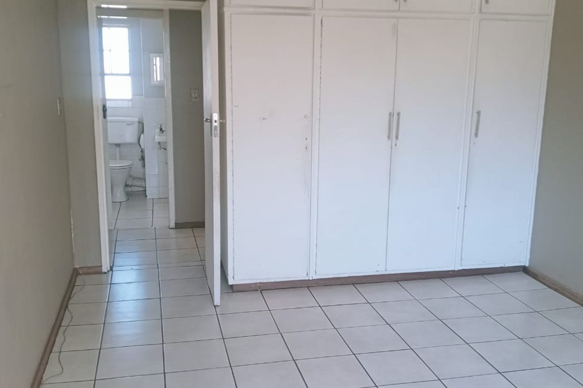 A bedroom featuring built-in floor-to-ceiling cupboards, tiled flooring, and direct access to an adjacent bathroom.