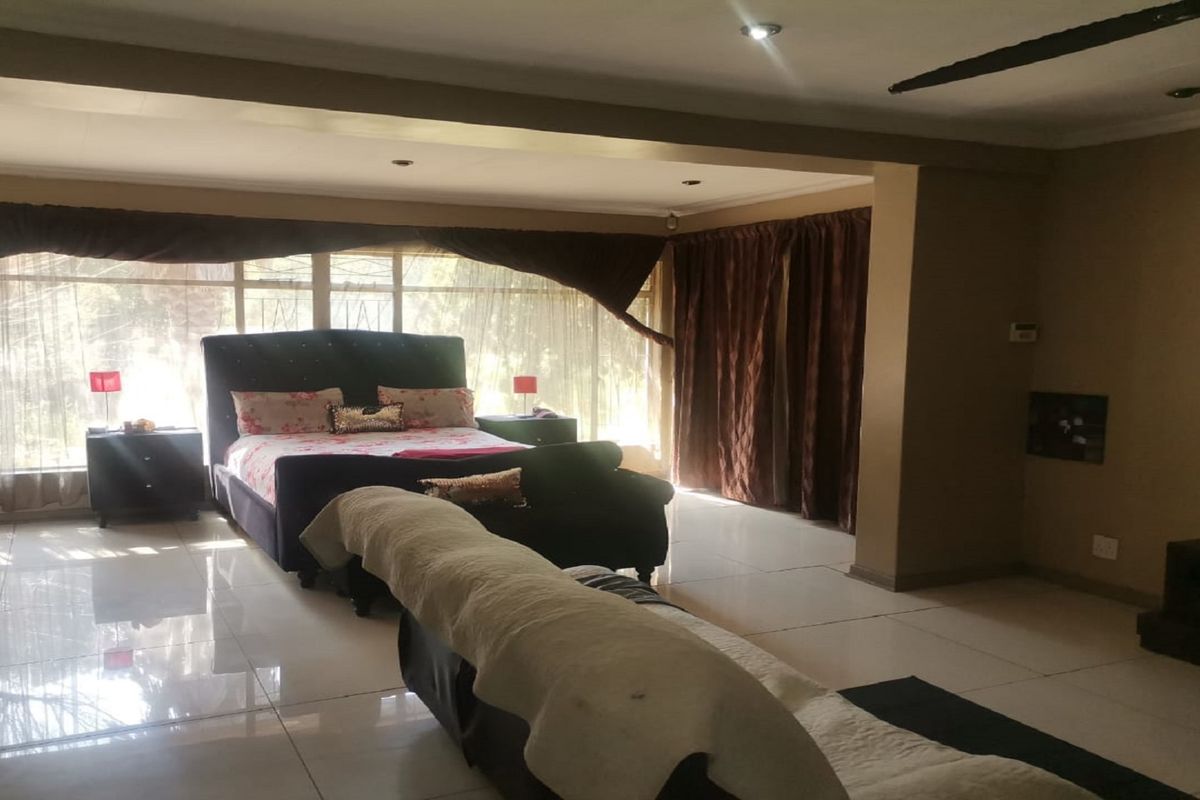 Spacious bedroom featuring large windows with natural light, tiled flooring, and recessed ceiling lighting.