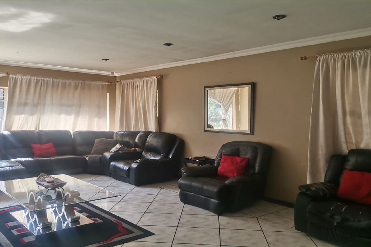 Spacious living room featuring tiled flooring, recessed ceiling lighting, and large windows with curtain treatments.