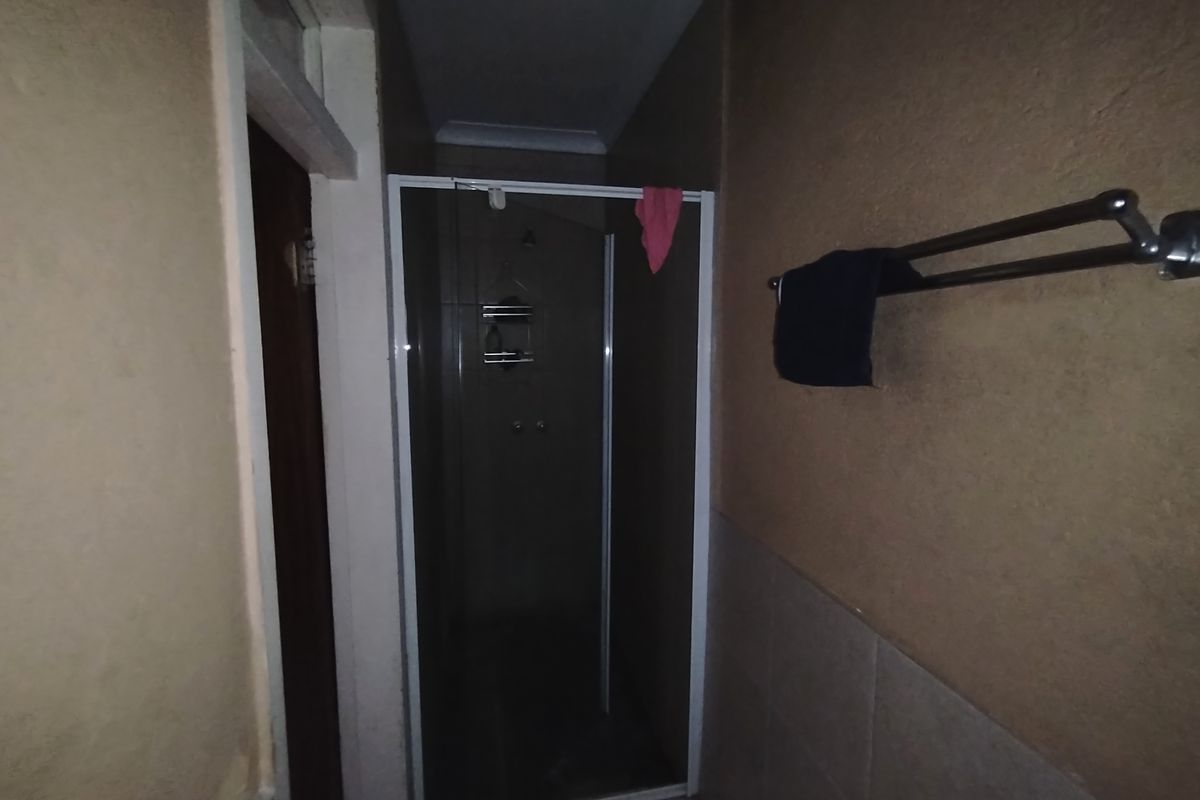 A compact bathroom featuring a glass-enclosed shower stall and a wall-mounted towel rail.