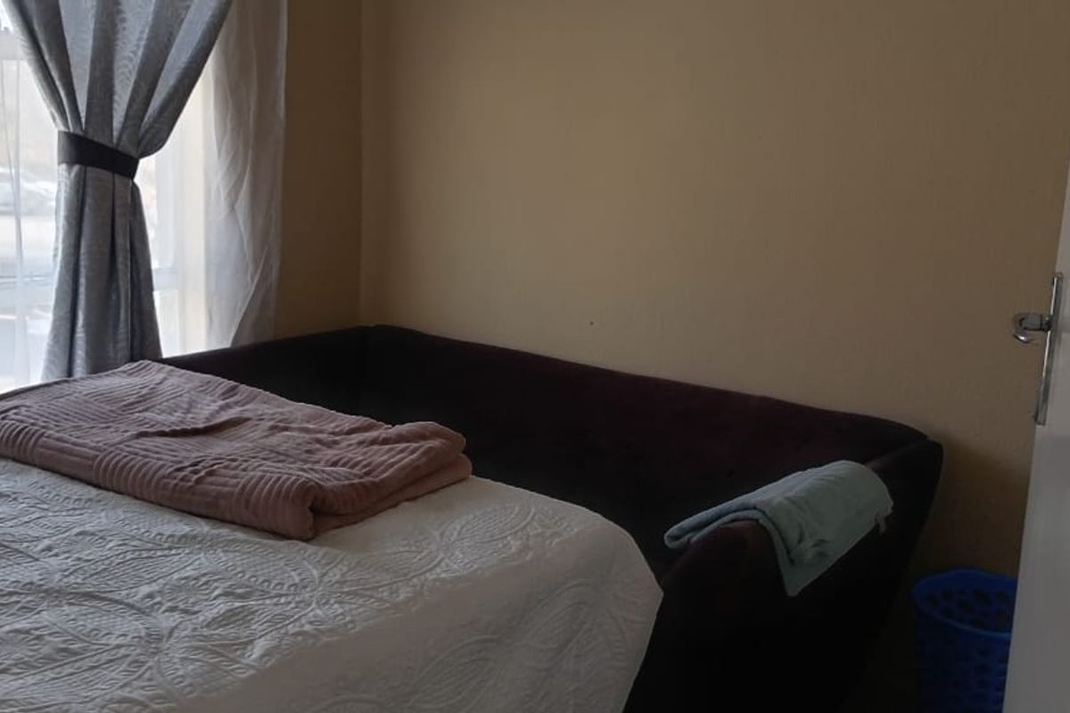 A bedroom featuring a window with curtains and a standard door, providing a functional living space.