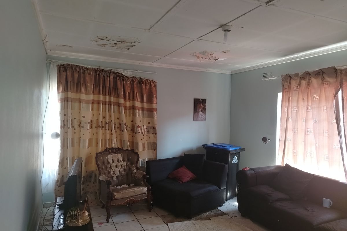 A living room featuring tiled flooring and significant water damage to the ceiling panels, requiring repair and refurbishment.