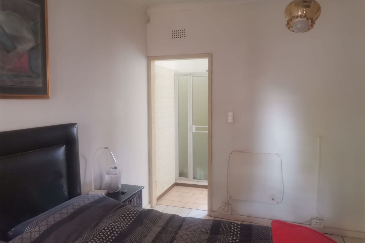 A bedroom featuring a doorway leading to an en-suite bathroom with a shower enclosure.