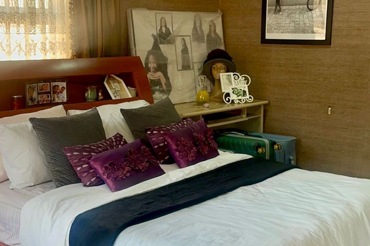 A bedroom featuring textured wall finishes, tiled flooring, and a built-in headboard with integrated shelving.