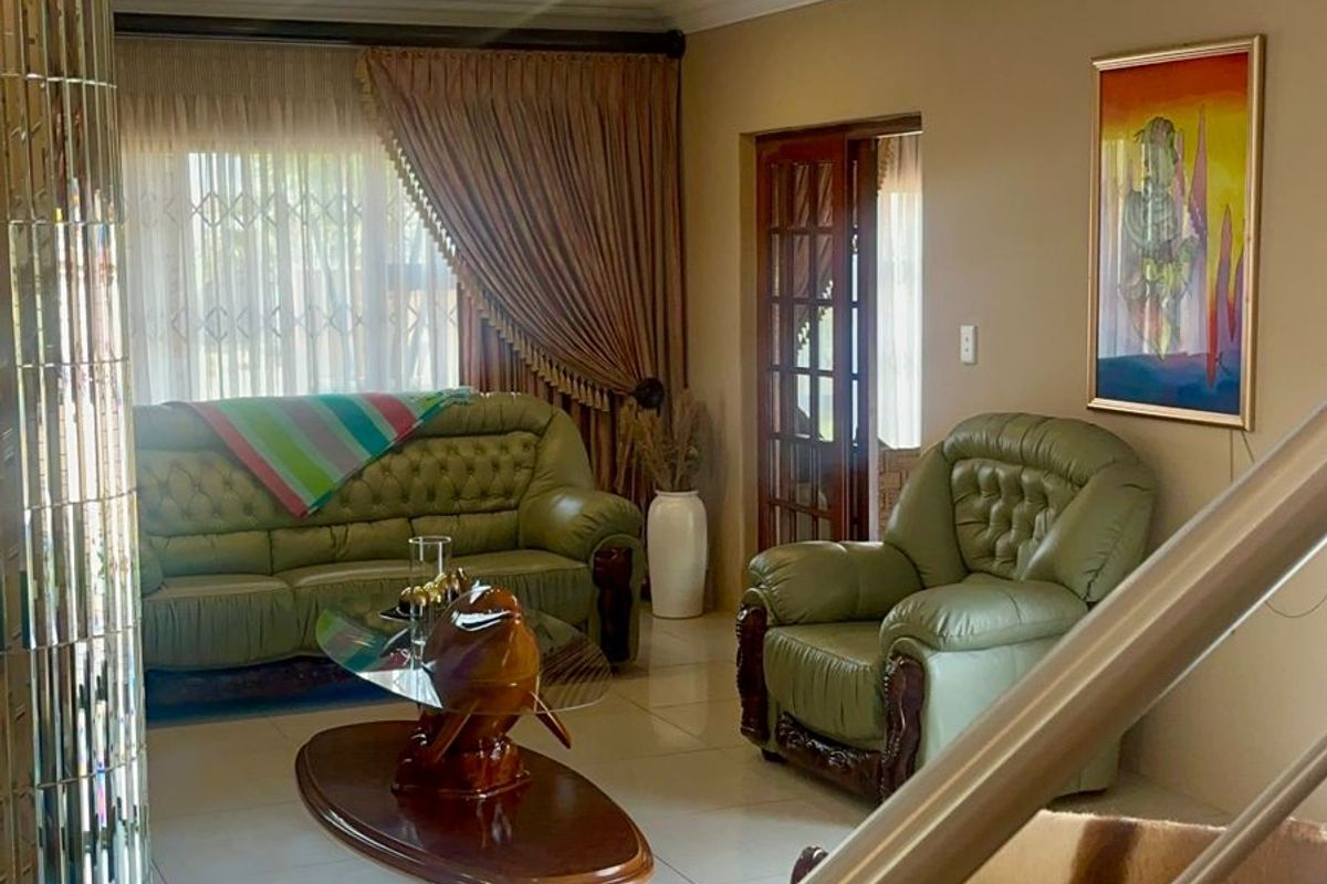 A comfortable living room featuring tiled flooring, recessed ceiling lighting, and a mirrored pillar, providing a warm and inviting space for relaxation.