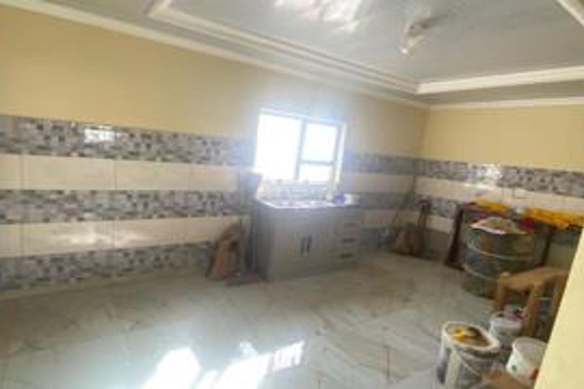 A functional kitchen area featuring tiled walls, a built-in sink unit, and tiled flooring, offering a practical space for food preparation.