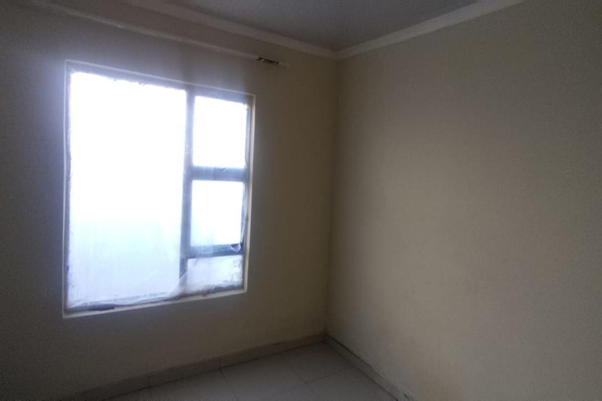 An empty bedroom featuring tiled flooring and a window with privacy film, offering a blank canvas for potential interior design updates.