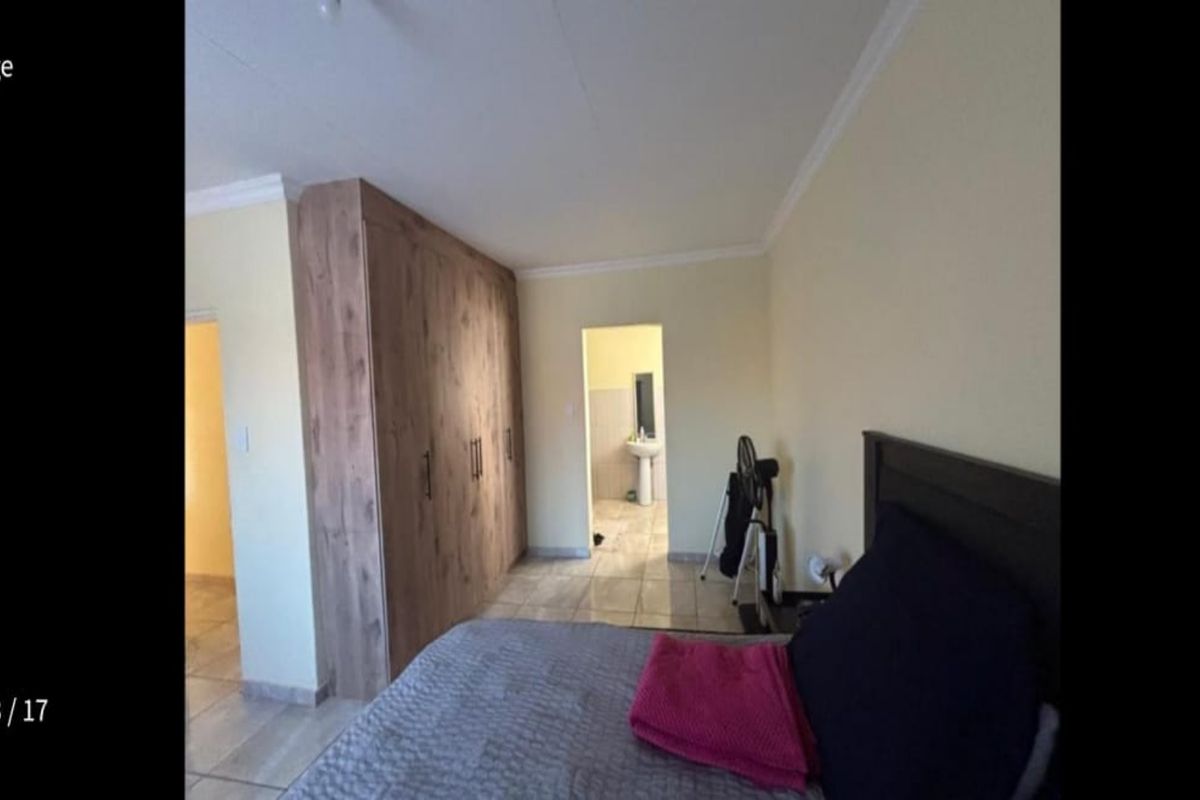 Bedroom featuring built-in wooden cabinetry and an adjoining en-suite bathroom with tiled flooring.