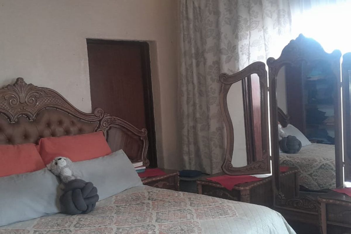 A bedroom featuring a window with curtains and a standard door, providing a functional living space.