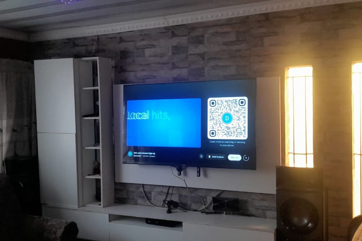 A living room featuring a stone-cladding feature wall with a built-in media unit and vertical accent windows.
