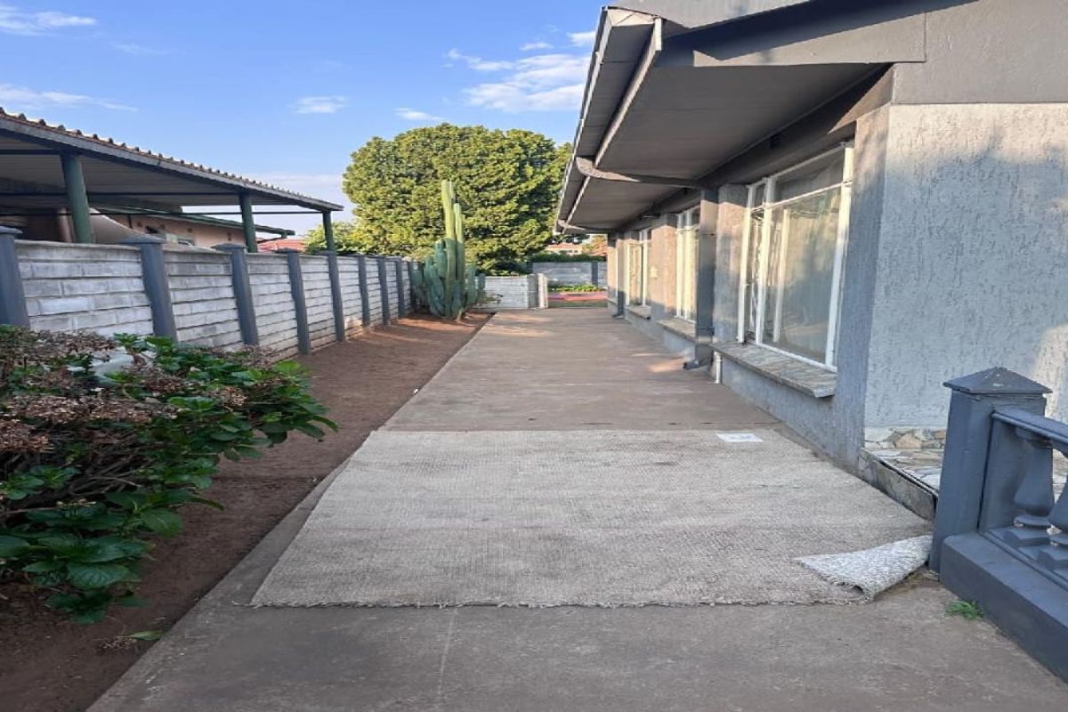 A side exterior view of the property featuring a concrete pathway, boundary wall, and access to the side of the house.