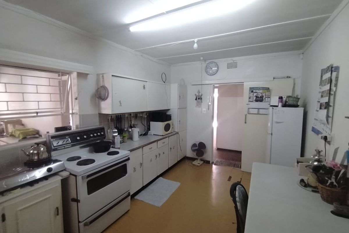 A functional kitchen featuring white cabinetry, a freestanding electric stove, and vinyl flooring, offering a practical layout with direct access to adjacent living areas.