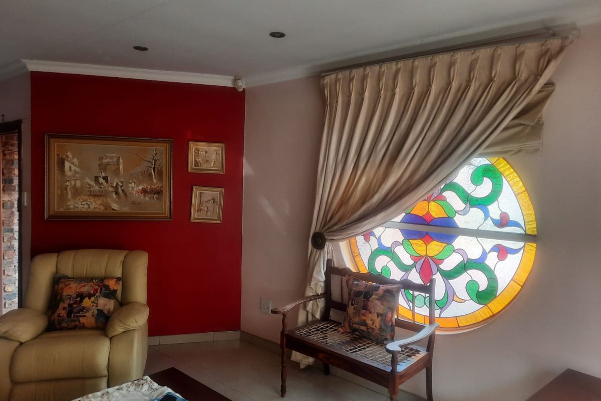 A living room area featuring a distinctive circular stained glass window, recessed ceiling lighting, and a bold red accent wall.