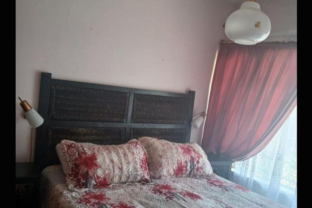 A bedroom featuring a pendant light fixture and window with curtain tracks.