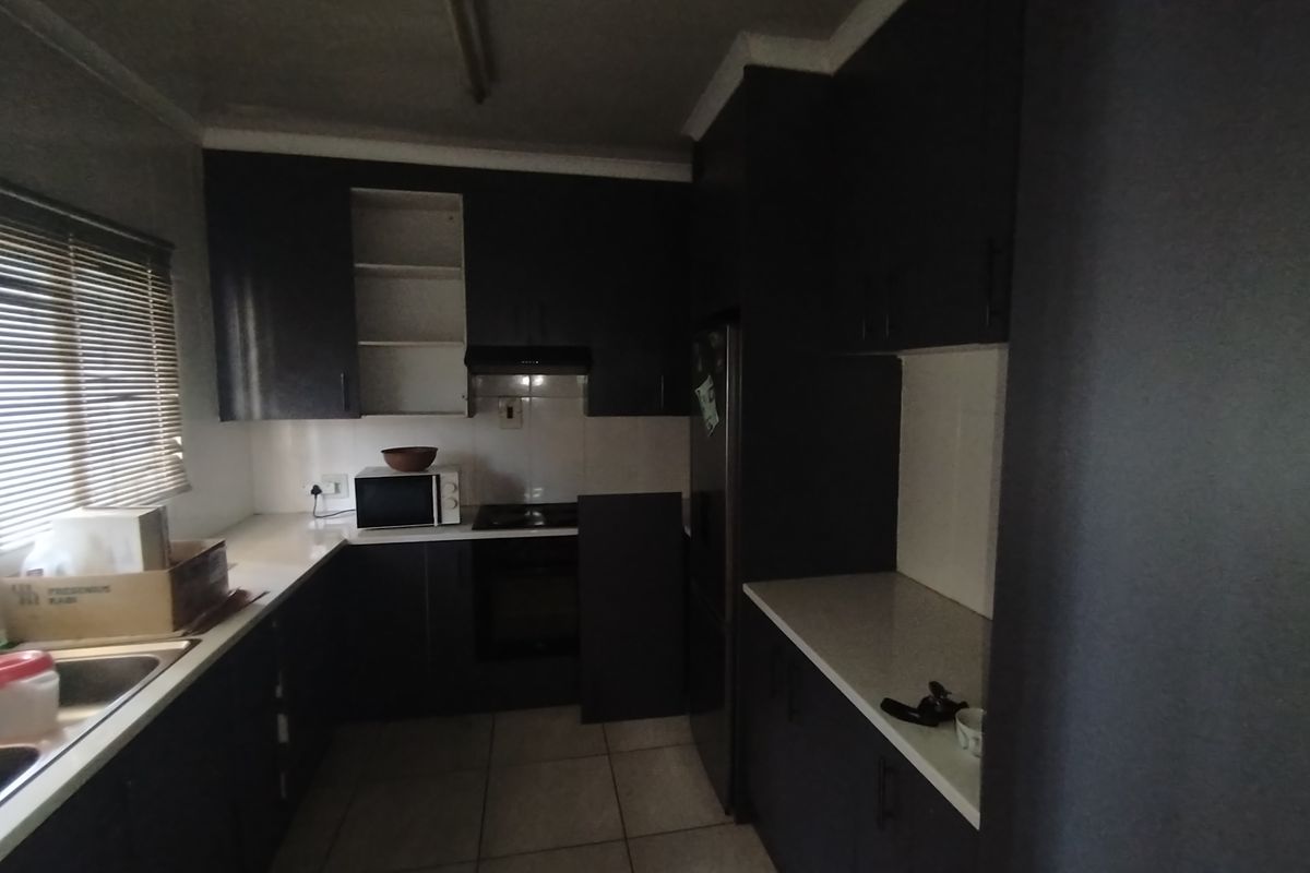 A functional kitchen featuring dark cabinetry, stone-look countertops, tiled flooring, and built-in oven and hob.