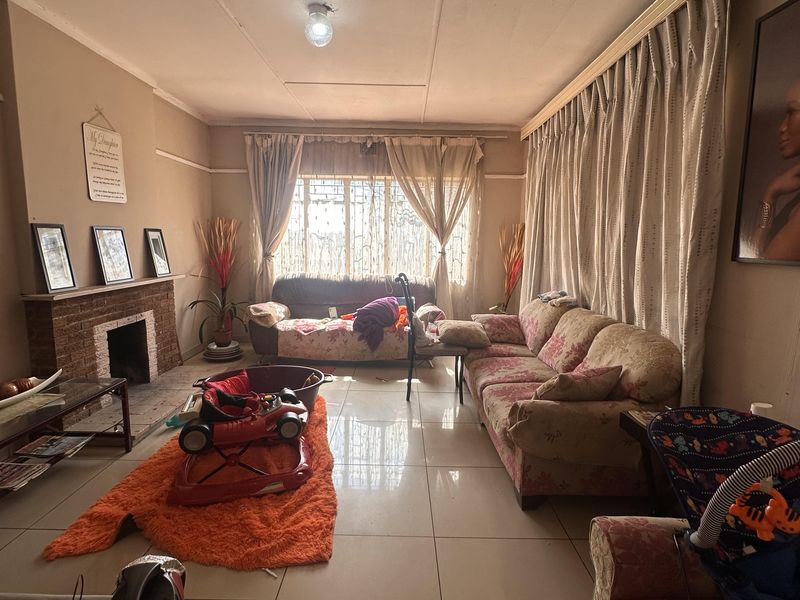 A living room featuring tiled flooring and a brick fireplace, requiring cosmetic updates to improve the overall aesthetic and condition of the space.