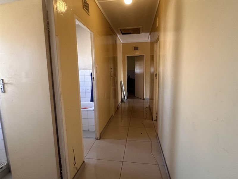 A long, tiled hallway providing access to multiple rooms, featuring neutral wall tones and standard internal door frames.