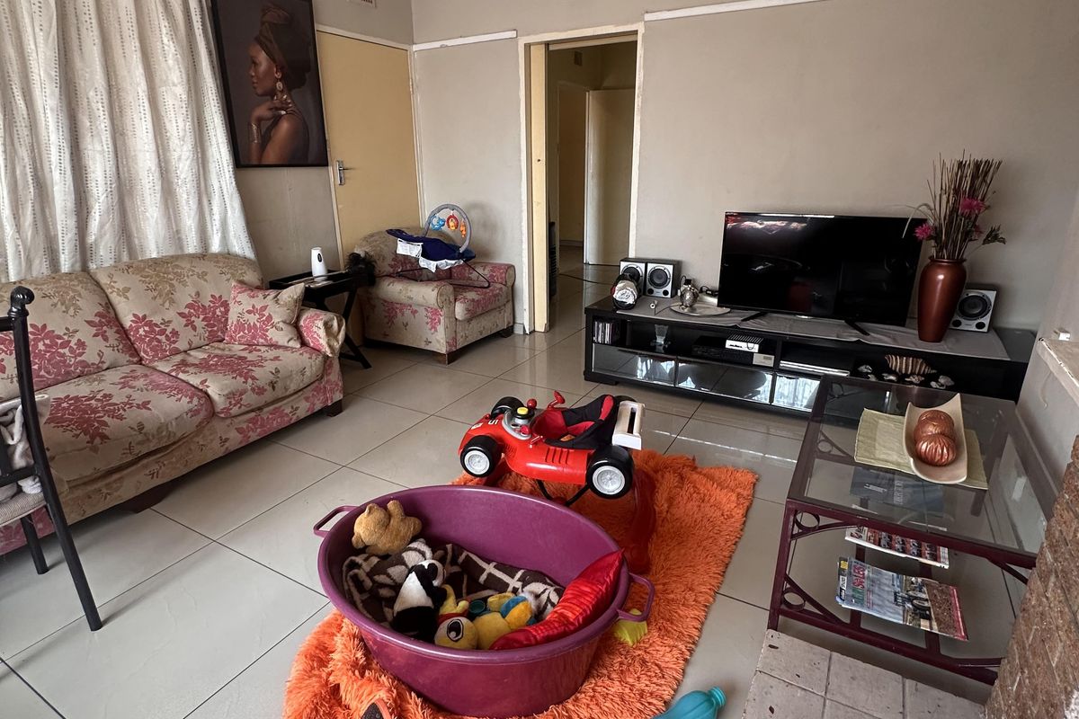 A living room featuring tiled flooring and a fireplace hearth, offering a functional space with potential for cosmetic updates.