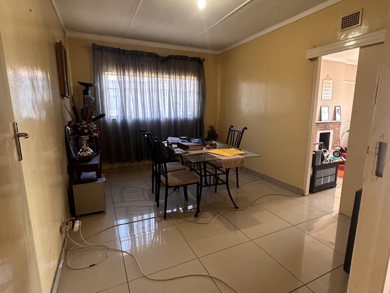 A functional dining room featuring large format floor tiles and neutral wall finishes, providing a clean base for potential interior updates.