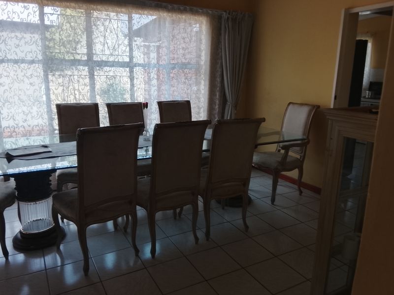 A dining room featuring tiled flooring and a large window, providing a functional space for family meals.