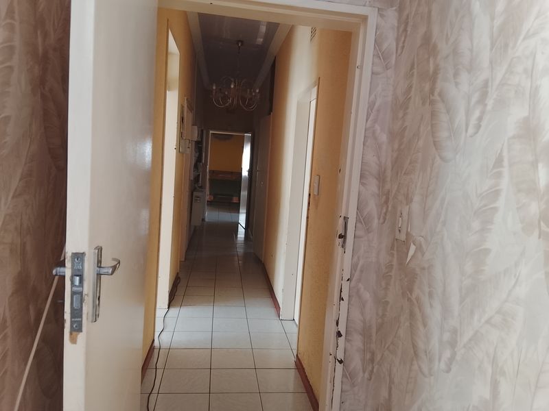 A long interior hallway featuring tiled flooring and neutral wall finishes, providing access to multiple rooms within the property.