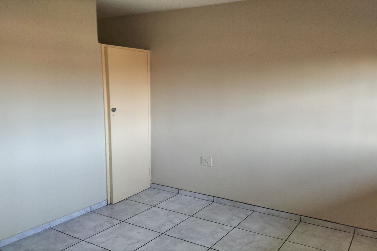 An empty bedroom featuring neutral wall paint, tiled flooring, and a single internal door.