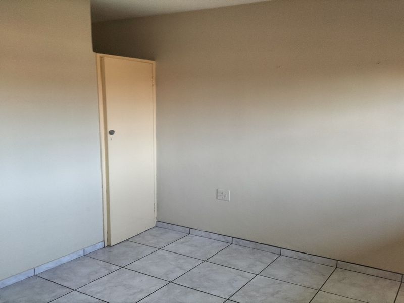 An empty bedroom featuring neutral wall paint, tiled flooring, and a single internal door.