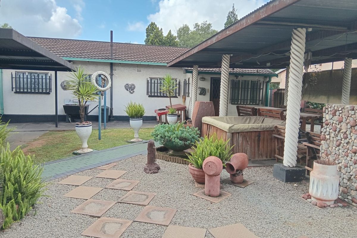 A covered outdoor patio area featuring decorative columns, paved pathways, and gravel landscaping, providing a functional space for outdoor relaxation and entertainment.