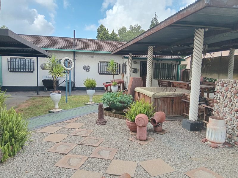 A covered outdoor patio area featuring decorative columns, paved pathways, and gravel landscaping, providing a functional space for outdoor relaxation and entertainment.