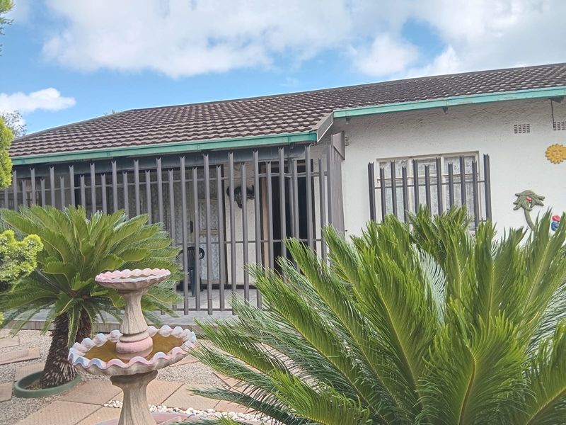 Front facade of the house featuring a tiled roof, security bars on windows and patio, and a landscaped garden with a concrete fountain.