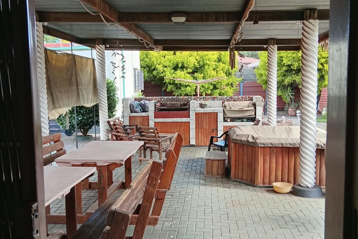 A covered outdoor patio area featuring paved flooring, built-in braai facilities, and timber support columns, ideal for outdoor entertaining.