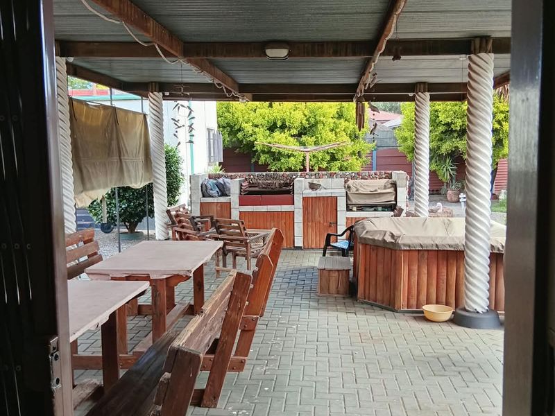 A covered outdoor patio area featuring paved flooring, built-in braai facilities, and timber support columns, ideal for outdoor entertaining.