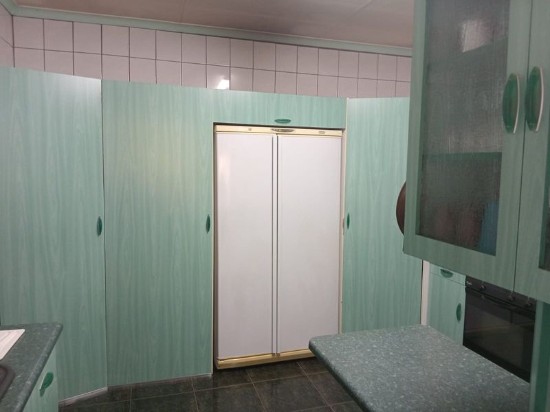 A dated kitchen featuring mint green cabinetry, tiled backsplash, and built-in oven, offering significant potential for a modern renovation.