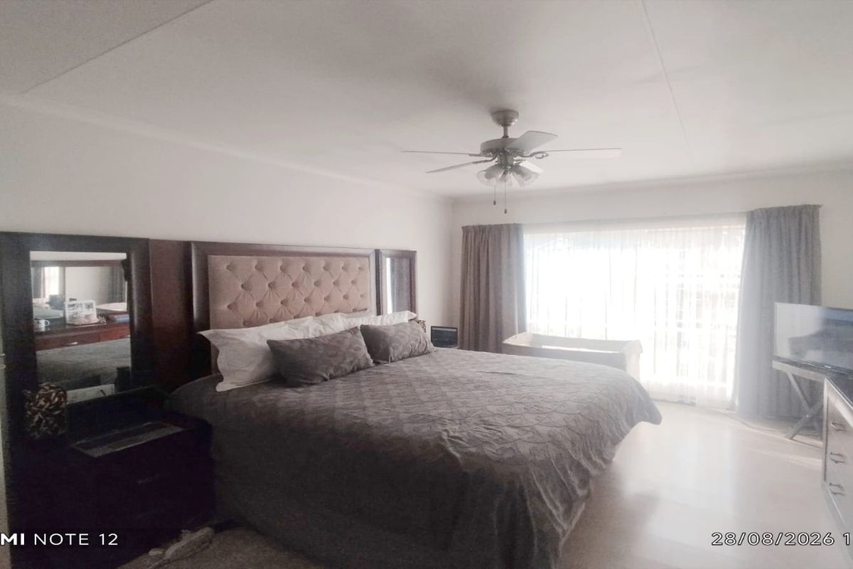Spacious bedroom featuring a ceiling fan and large sliding glass doors that provide ample natural light.