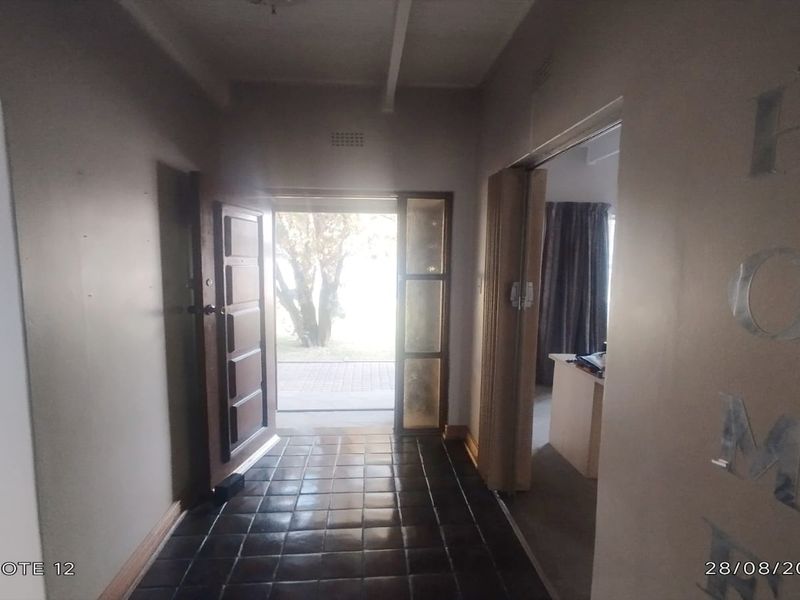 An entry hallway featuring dark tiled flooring and a timber front door, leading into the main living areas of the home.