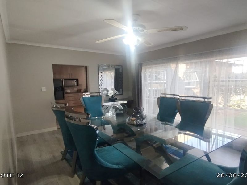 A well-lit dining room featuring a ceiling fan, neutral wall tones, and large sliding glass doors providing natural light and access to the exterior.