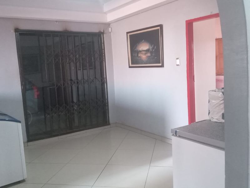 A living area featuring tiled flooring, a security gate, and a sliding door leading to an exterior space.