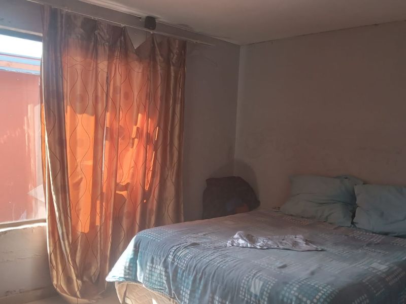A bedroom featuring a window with a curtain rail, requiring cosmetic updates to the wall finishes to improve the overall aesthetic.