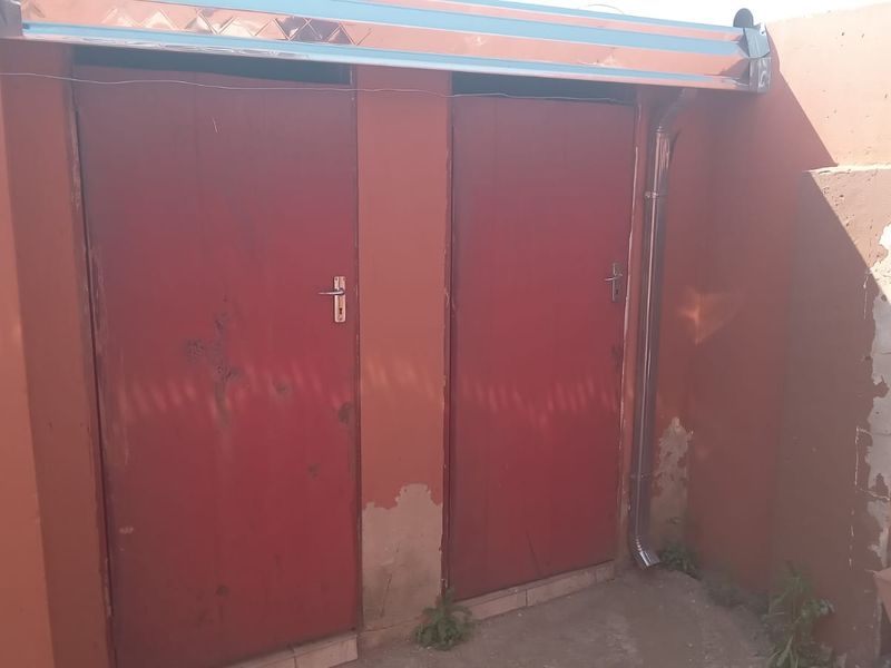 Exterior view of two utility doors with visible wear to the surrounding wall render and paintwork.