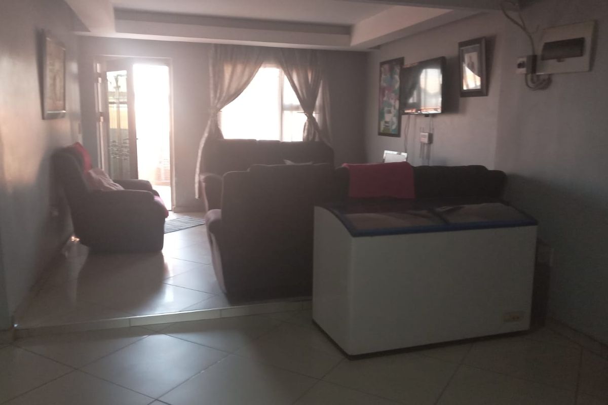 A living room area featuring tiled flooring and a recessed ceiling detail, with direct access to an outdoor space.