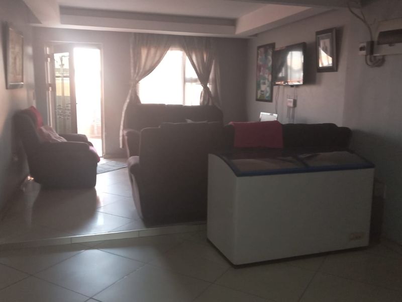 A living room area featuring tiled flooring and a recessed ceiling detail, with direct access to an outdoor space.