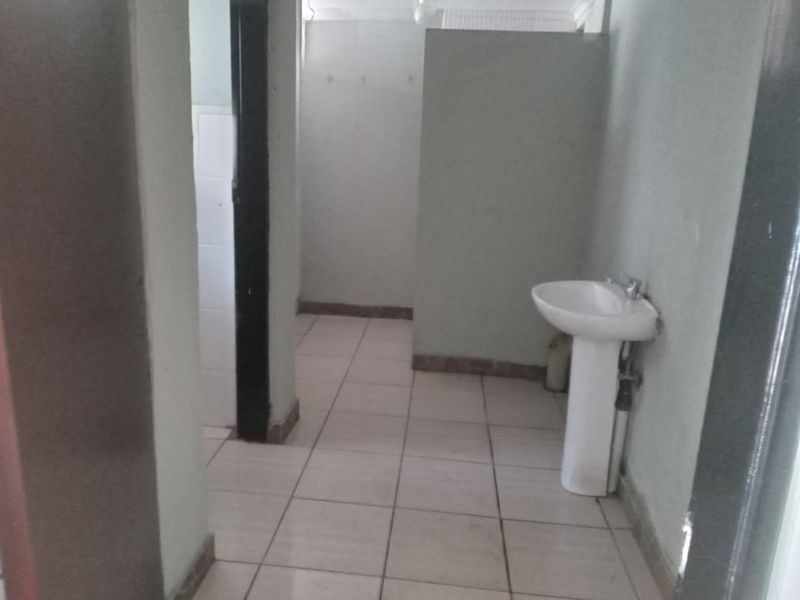 A basic, empty bathroom featuring a pedestal basin and tiled flooring, requiring cosmetic updates to improve its overall condition and appeal.