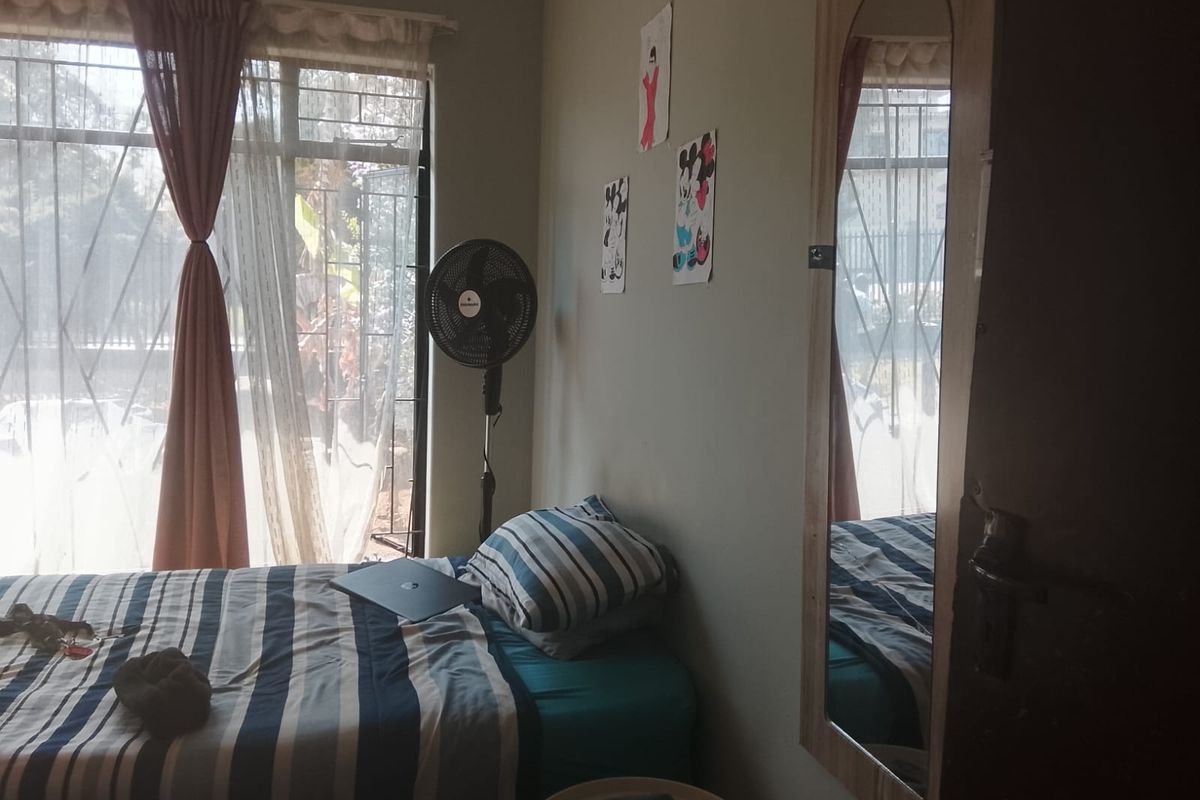 A bedroom featuring a large window with security bars and a built-in mirror on the door.