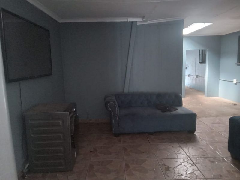 A living area featuring tiled flooring and a skylight, currently showing signs of wear with exposed conduit and dated wall finishes.