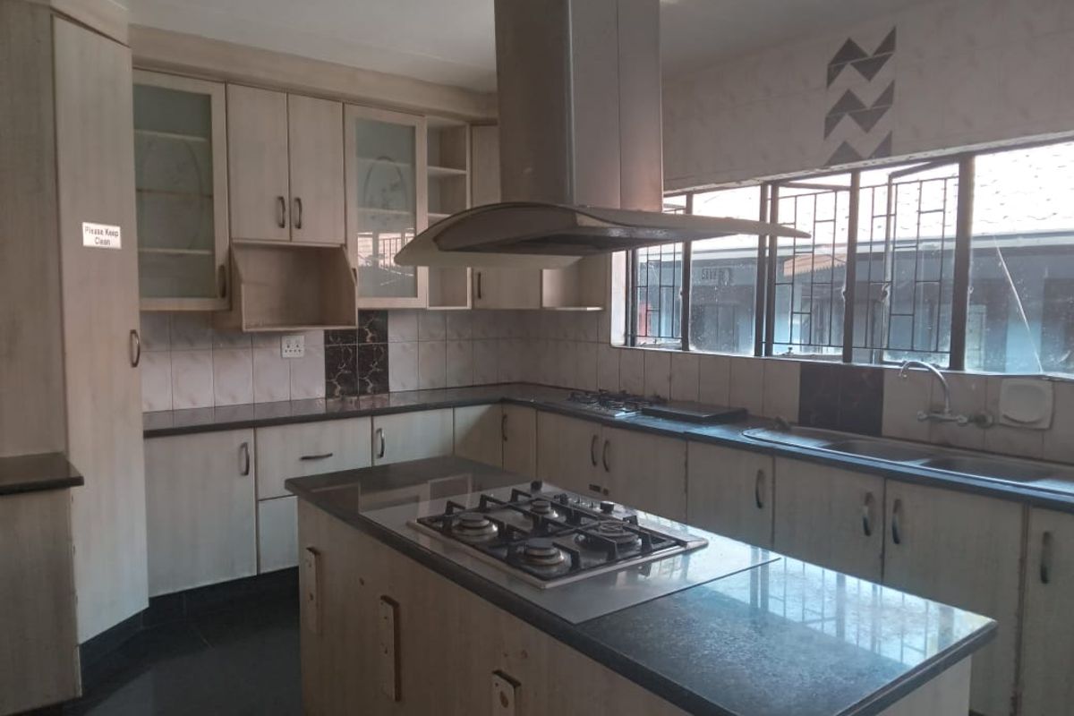 Spacious kitchen featuring a central island with a gas hob, extractor fan, granite countertops, and ample built-in cabinetry.